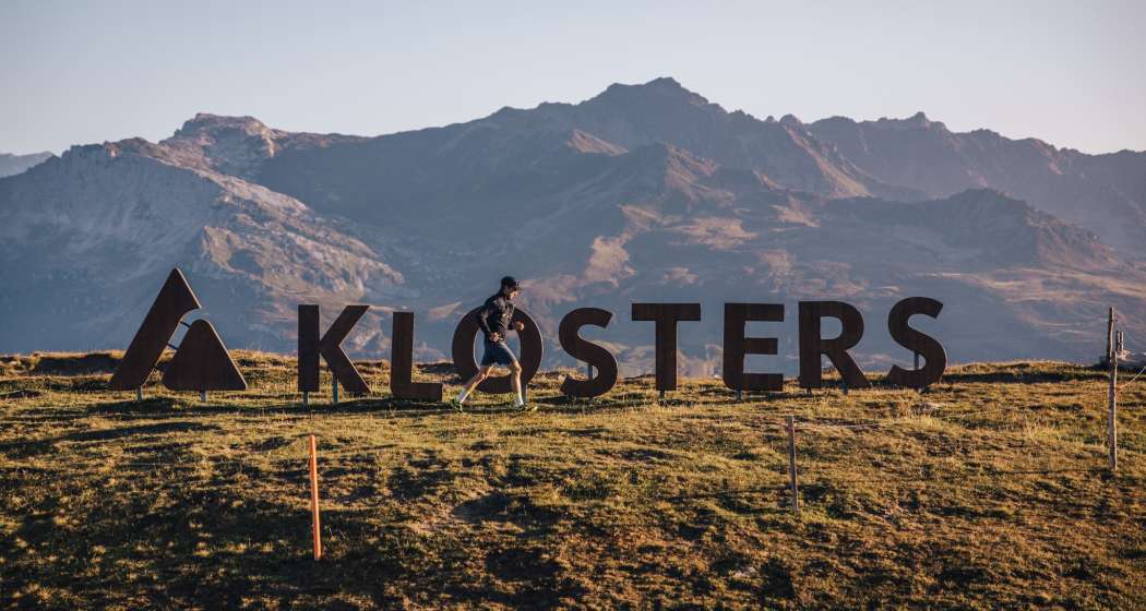 Ein Trailrunner läuft vor dem Klosters-Logo auf dem Gotschna Ein Trailrunner läuft vor dem Klosters-Logo auf dem Gotschna