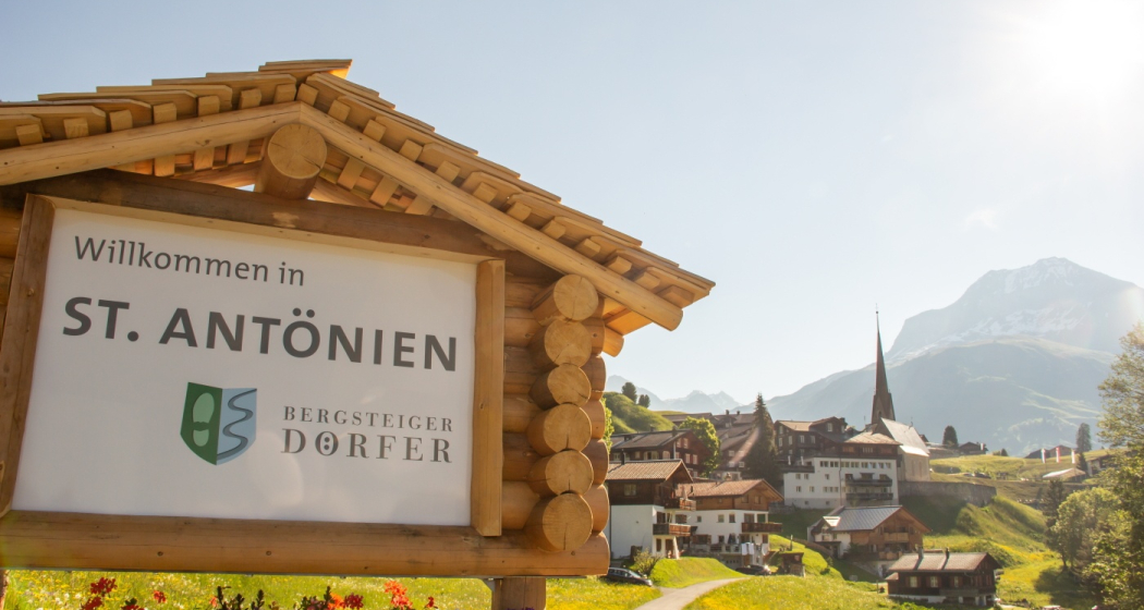 Ortstafel des Bergsteigerdorfes St. Antönien, im Hintergrund das Dorf Ortstafel des Bergsteigerdorfes St. Antönien, im Hintergrund das Dorf