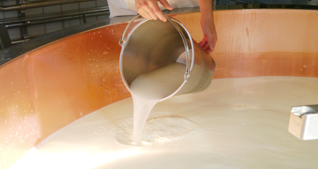 Das Foto zeigt ein Mitarbeiter der Milch in eine große Maschine eingießt Das Foto zeigt ein Mitarbeiter der Milch in eine große Maschine eingießt