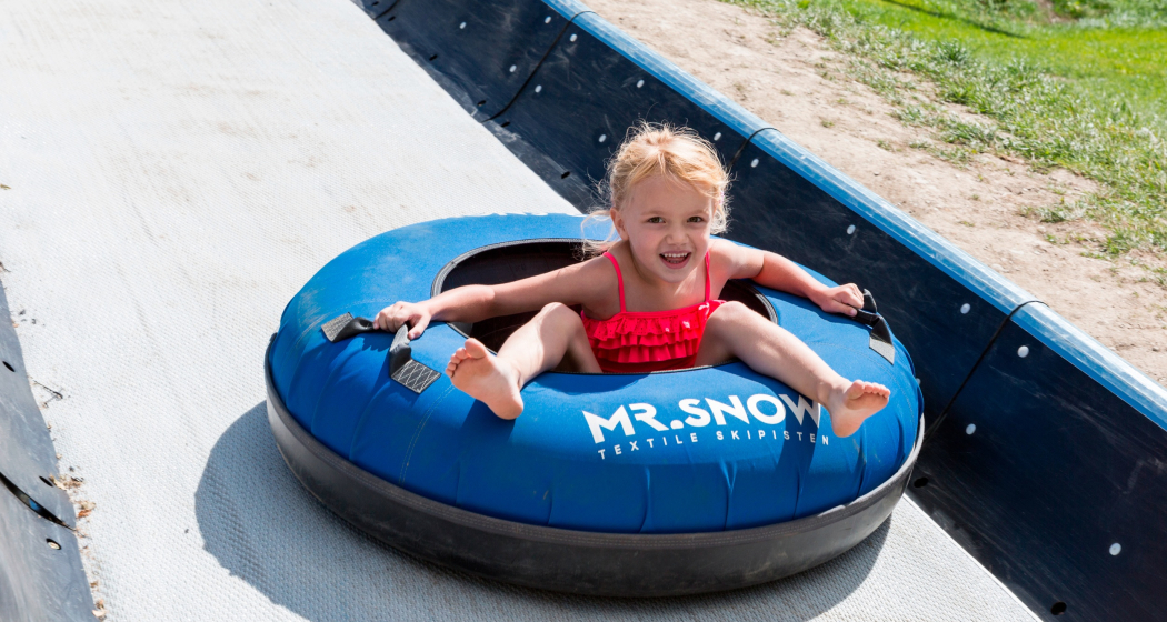 Das Foto zeigt ein junges Mädchen, welches die Tubingbahn runter fährt Das Foto zeigt ein junges Mädchen, welches die Tubingbahn runter fährt